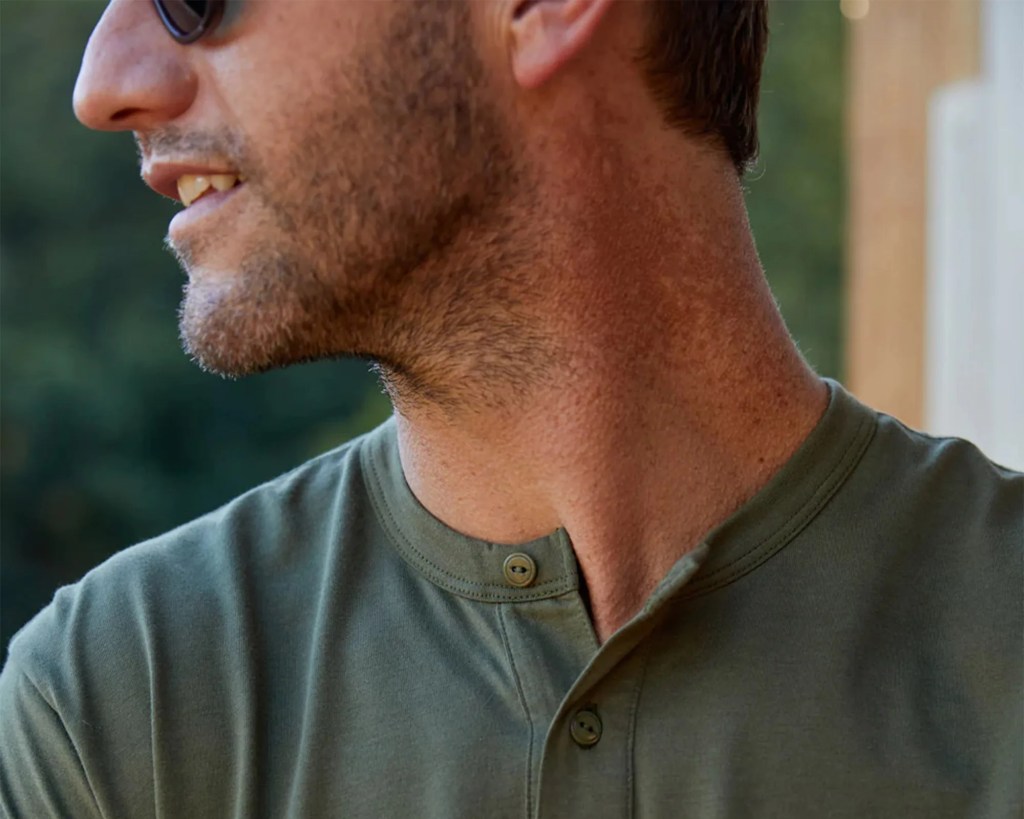 man turned to the side wearing sunglasses and green Outerknown long sleeve