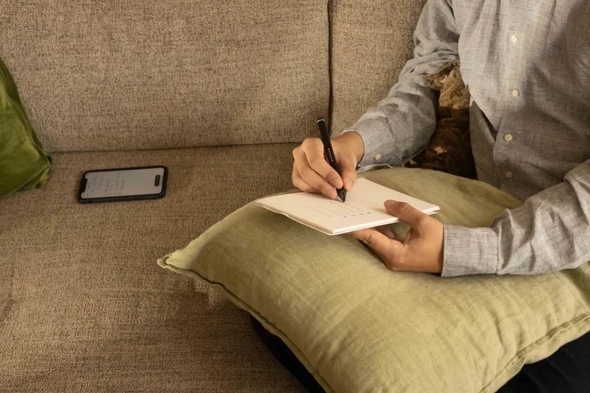 a person writing on a book using a nuwa pen