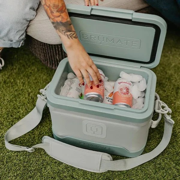 a person putting a drink into a magpack 12 can shoulder sling soft cooler