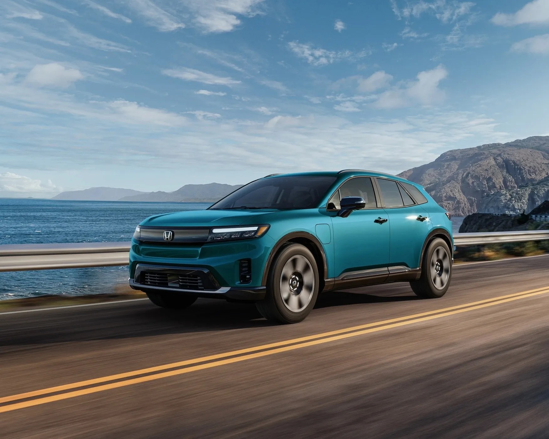 a blue honda prologue EV driving on a highway by the ocean