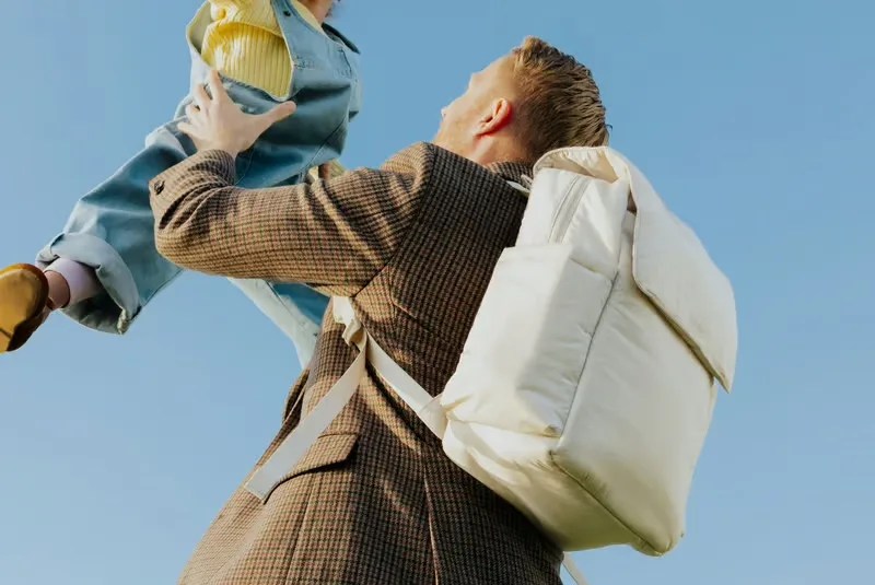 man holding child up while wearing CALPAK bag