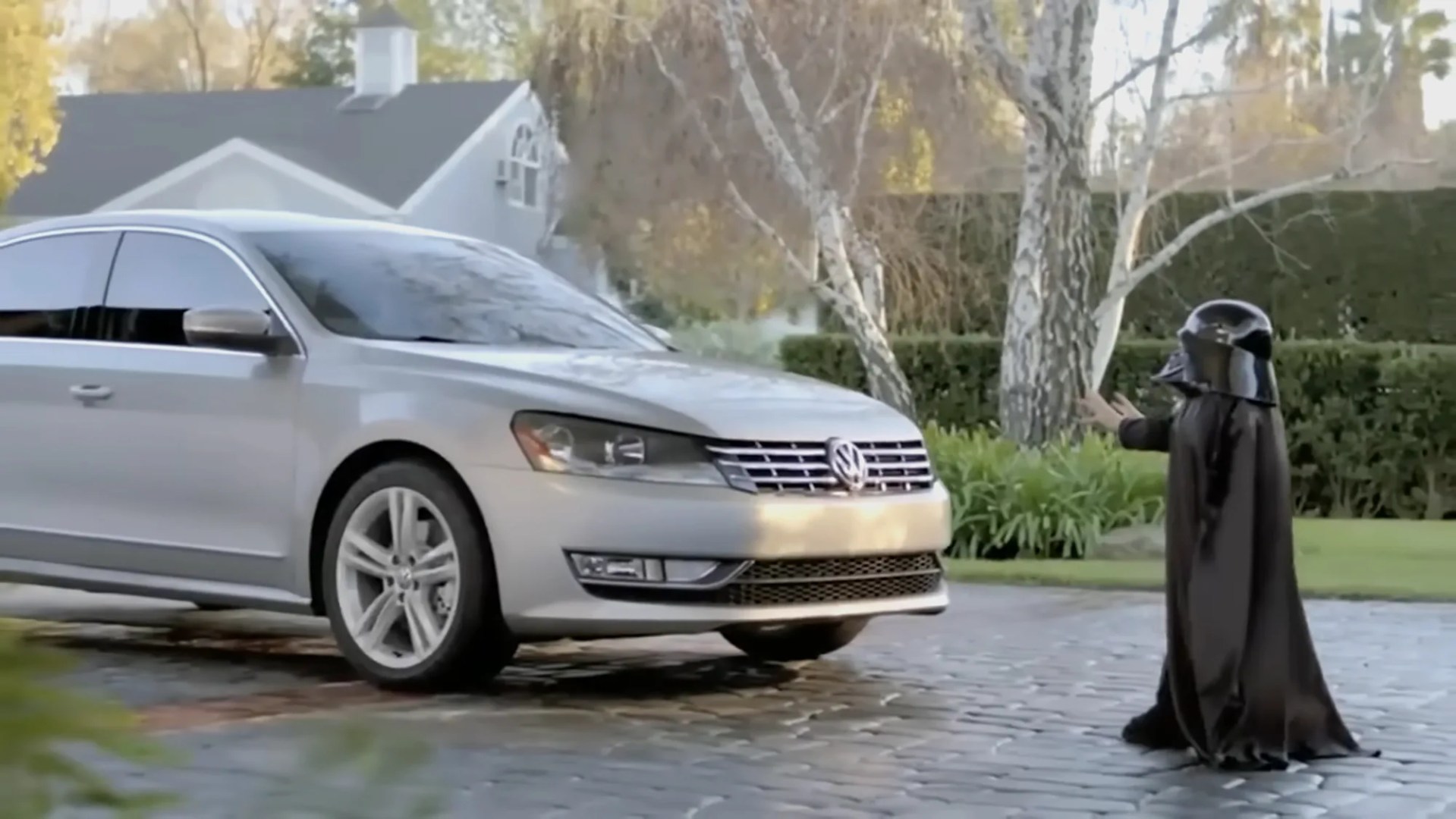 a boy in a darth vader costume attempting to use the force to start a volkswagen passat