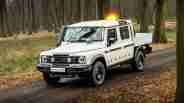 Ineos Grenadier Quartermaster chassis cab pickup driving through woods