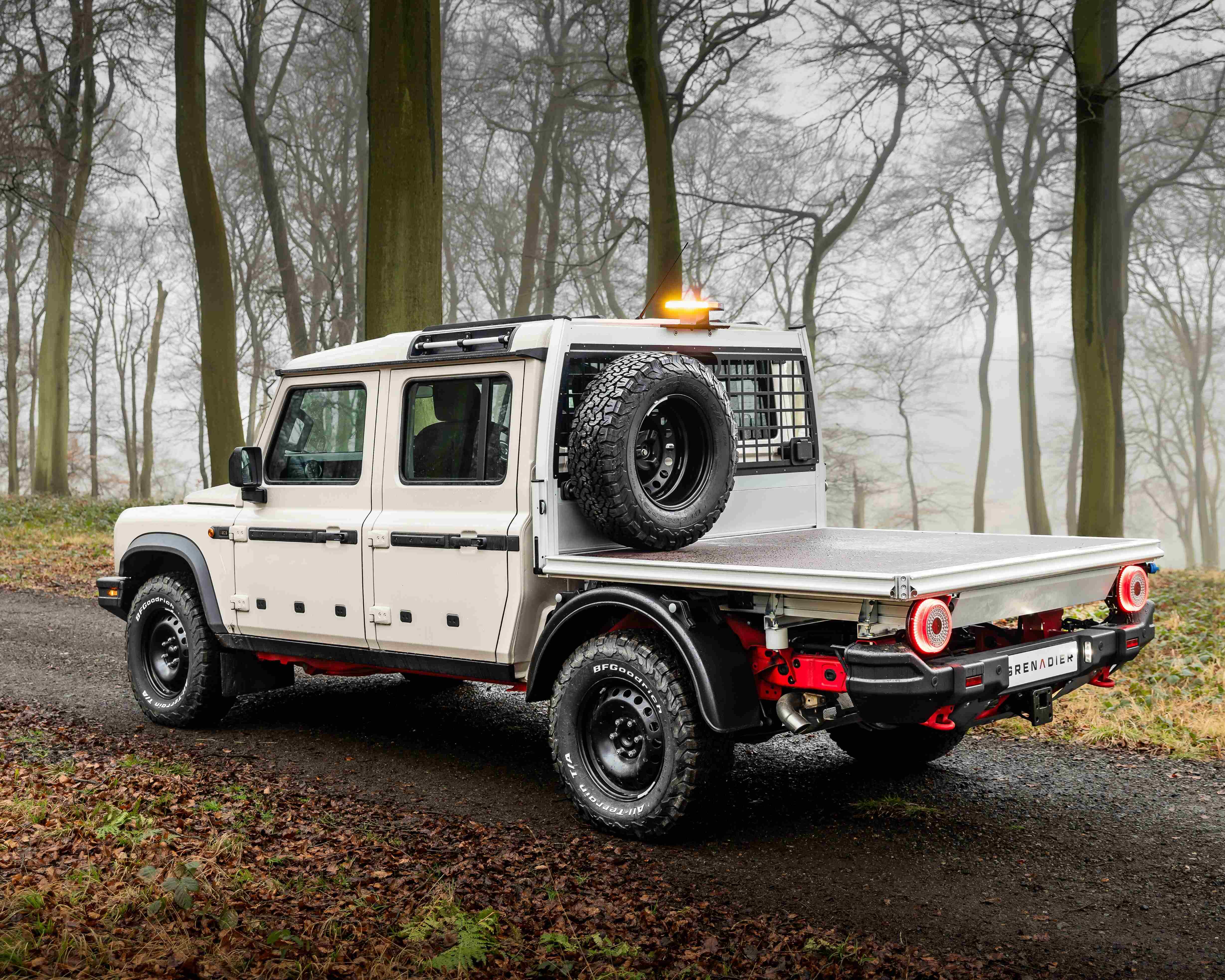 rear of ineos quartermaster chassis cab pickup in foggy woods