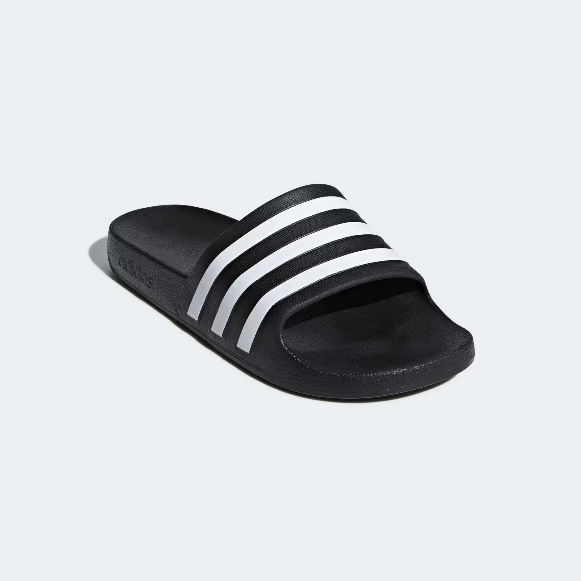 Black Adidas slide sandal with three white stripes across the strap on a light gray background.