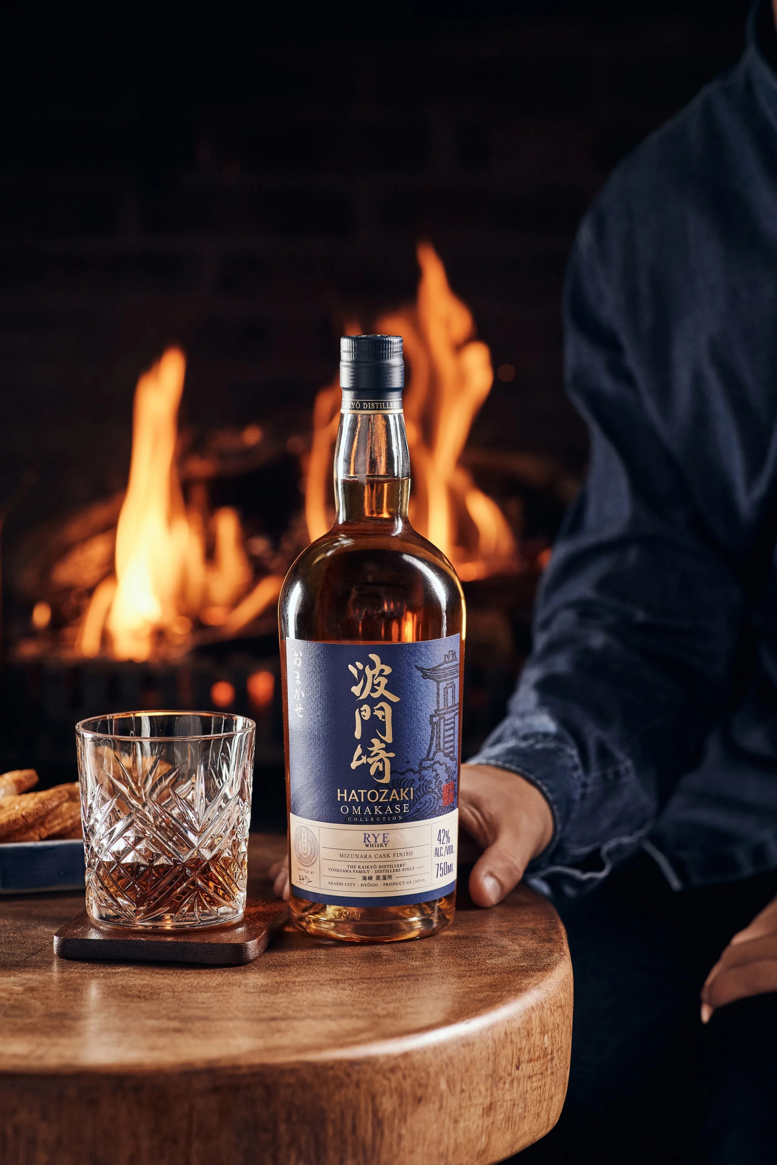 Hatozaki Omakase Rye bottle on table in front of fire