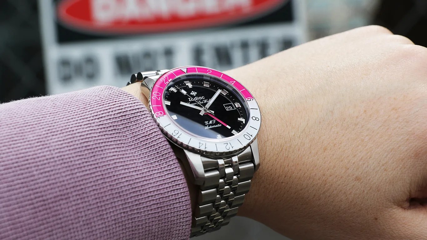 zodiac watch on mans wrist in front of danger sign