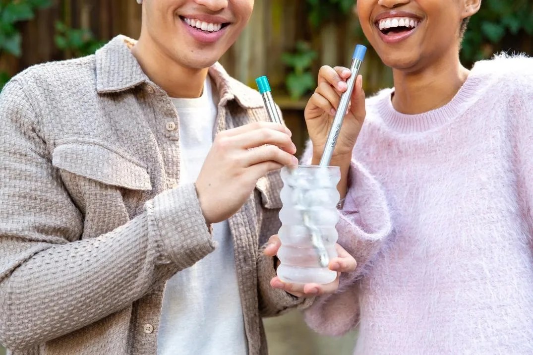 LifeStraw Sip filter straw being used by two smiling people in water drinking glasses.