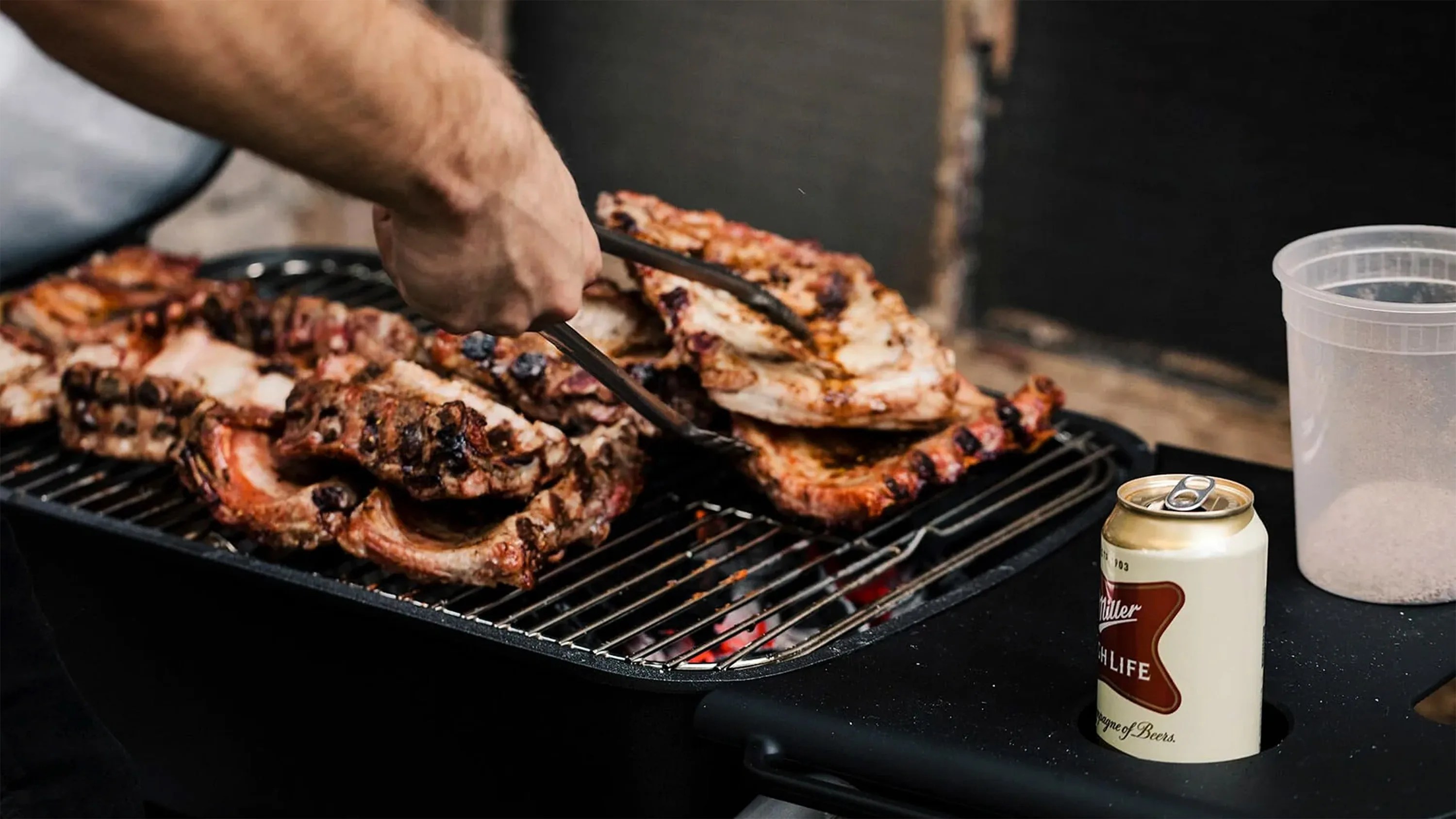 person cooking ribs on a grill