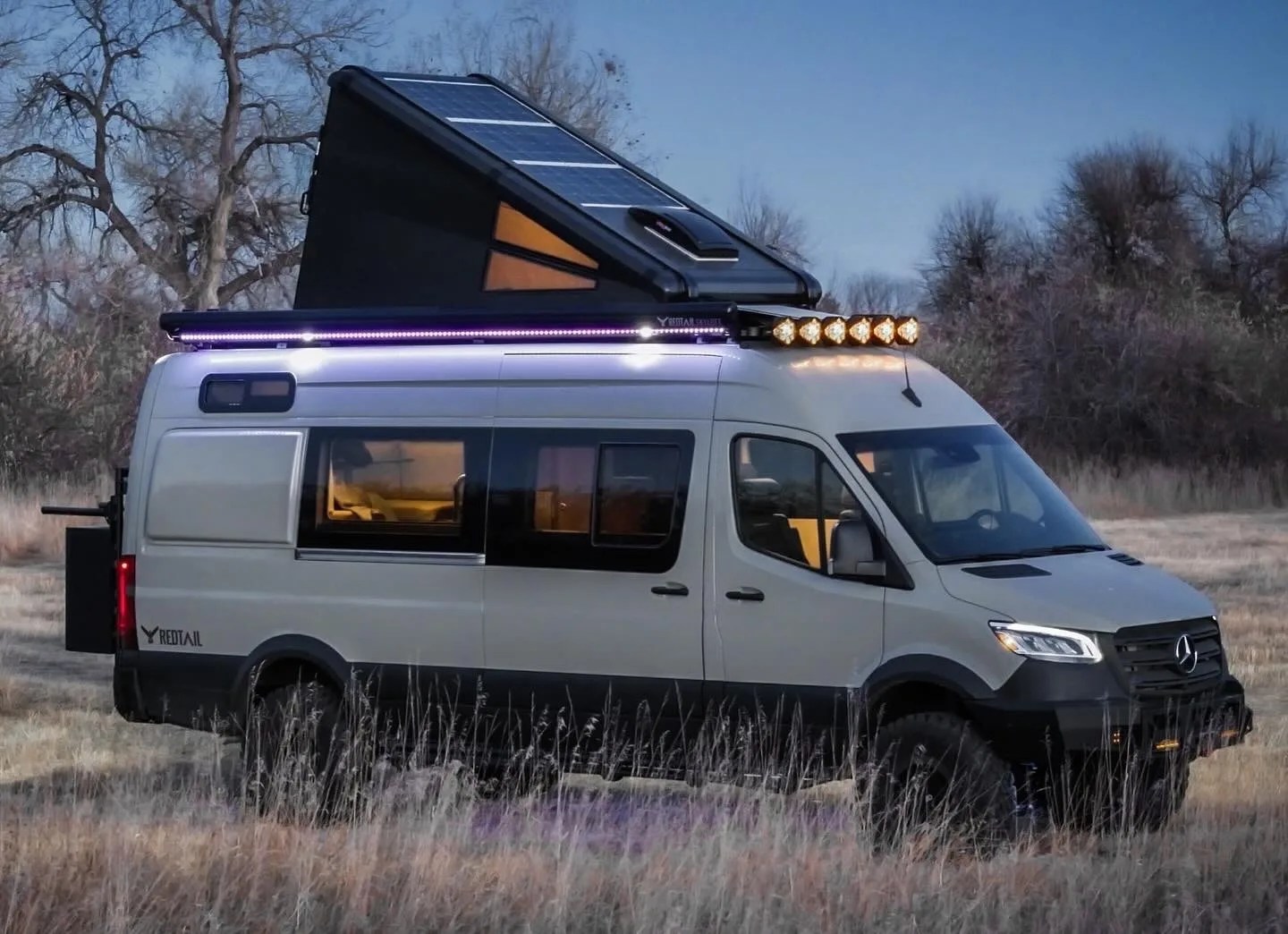 redtail overland camper van with rooftop tent in a field