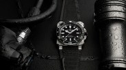 a black bell and ross dive watch lies next to some black gear