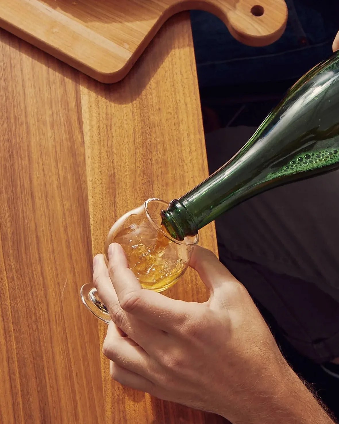 person pouring beer into a small glass