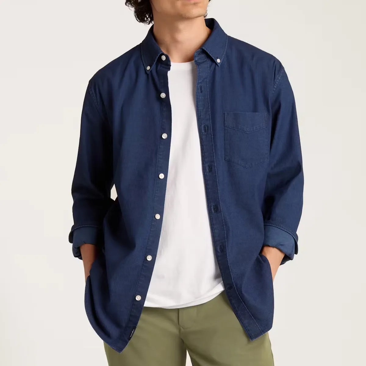 Navy blue button-up shirt with chest pocket worn open over a white t-shirt and olive pants.