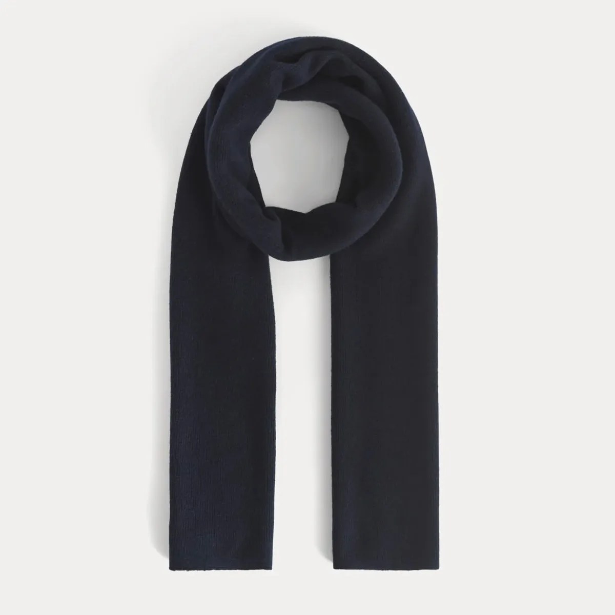Dark navy blue knitted scarf laid flat with one end looped.