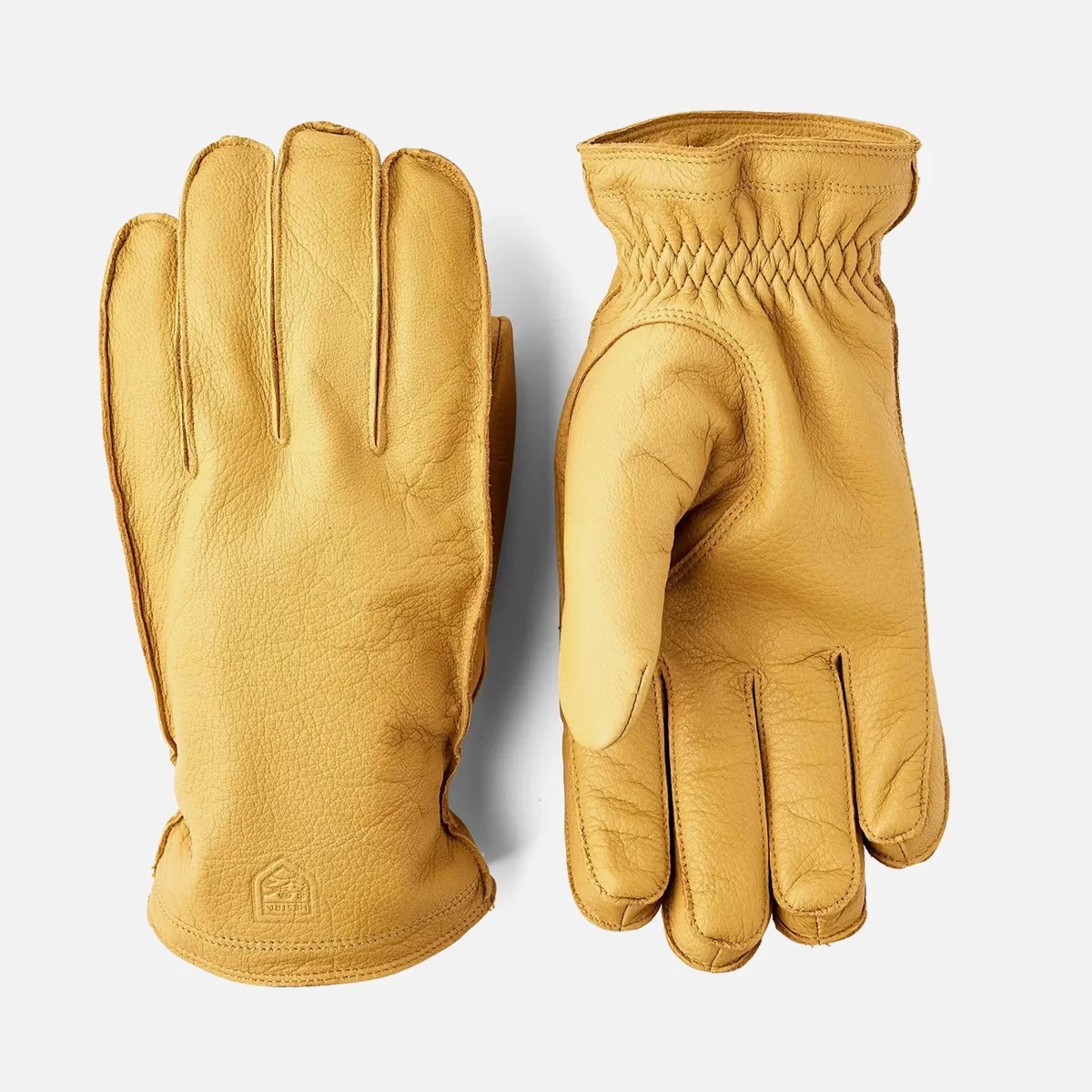 Pair of tan leather gloves with elasticized wrists, one showing palm side and the other back side.