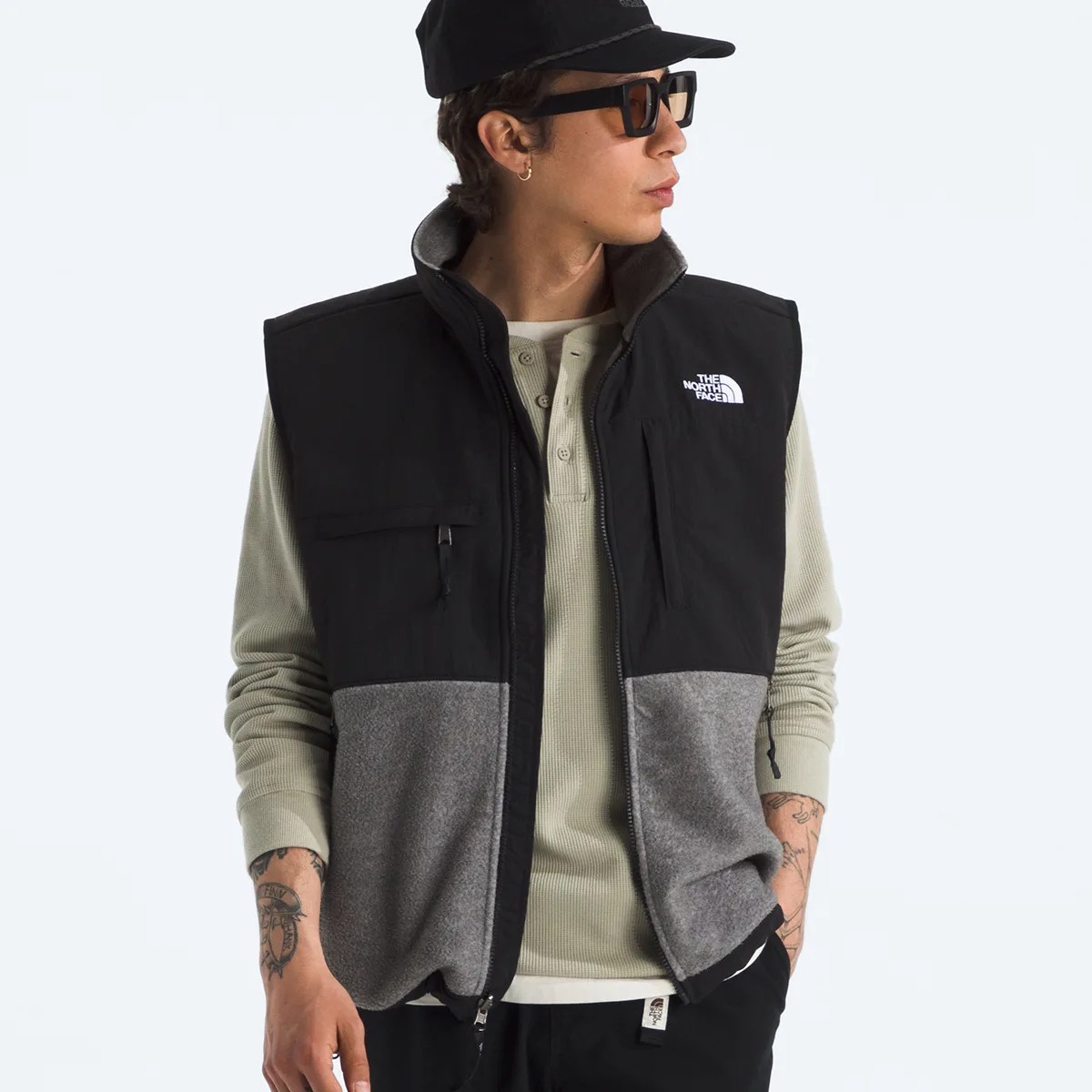 Black and gray fleece vest with The North Face logo worn over a light green long-sleeve shirt.