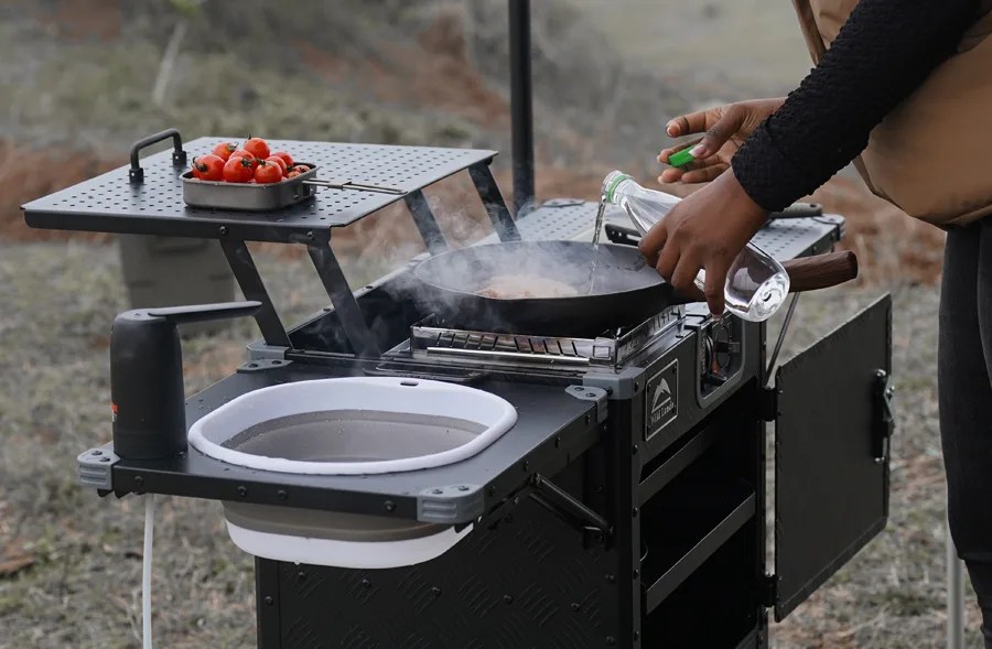 person cooking with a cinch x wild land outdoor kitchen