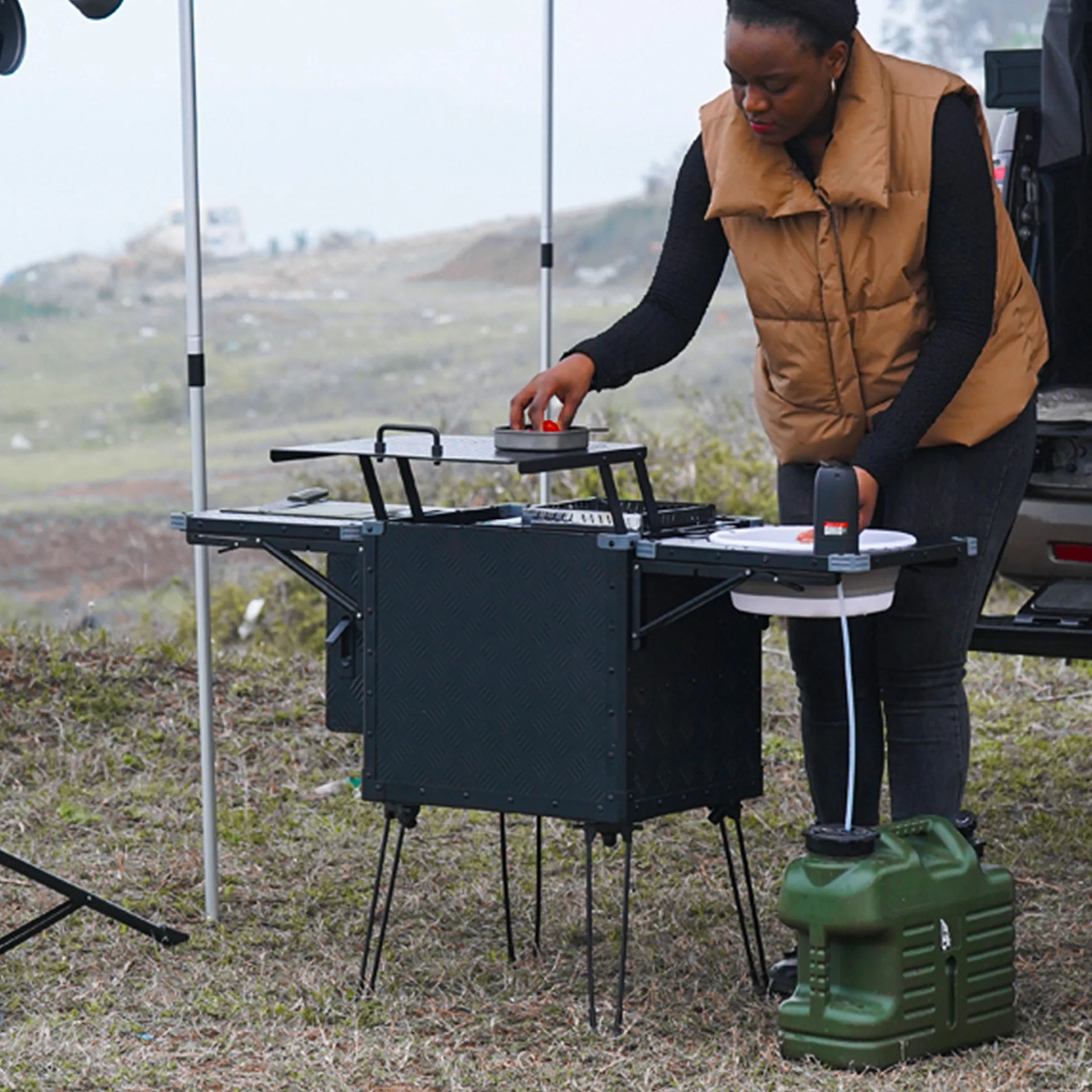 a woman uses a foldable camp kitchen outdoors