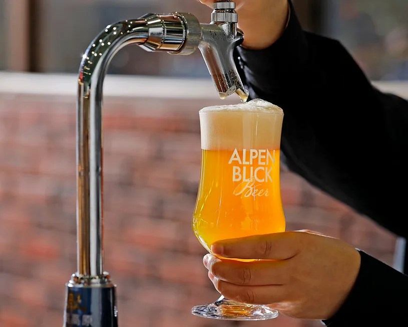 person pouring a glass of beer from a draft