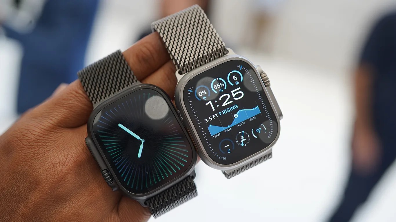 a hand holds two apple watches on mesh straps