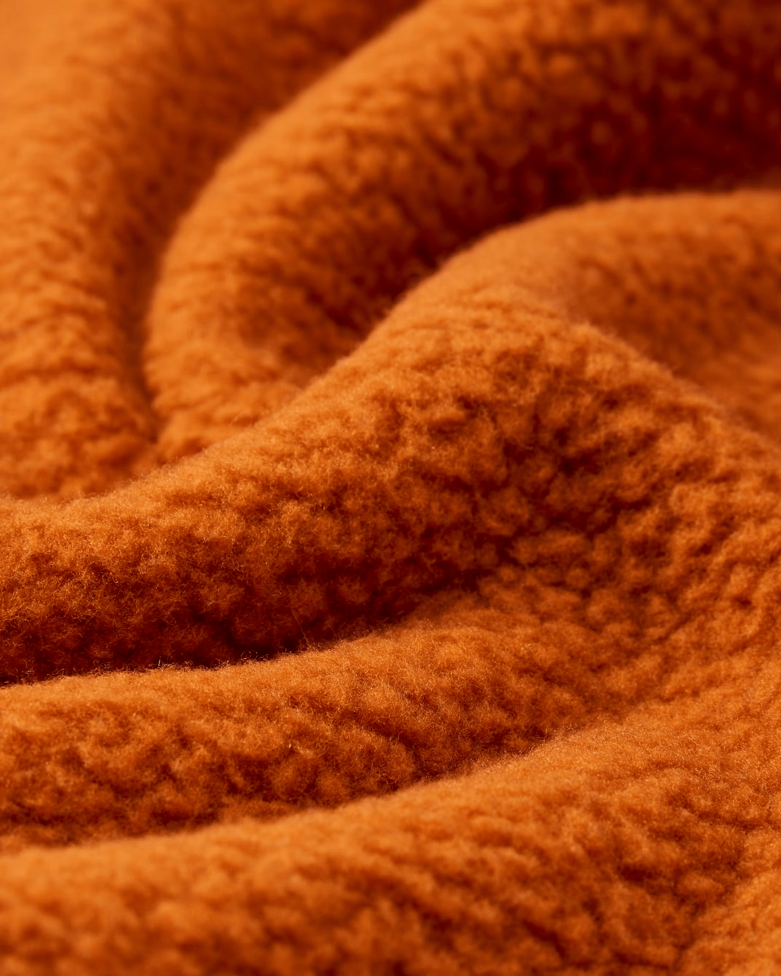 A close up image of orange fleece fabric to highlight the tufts