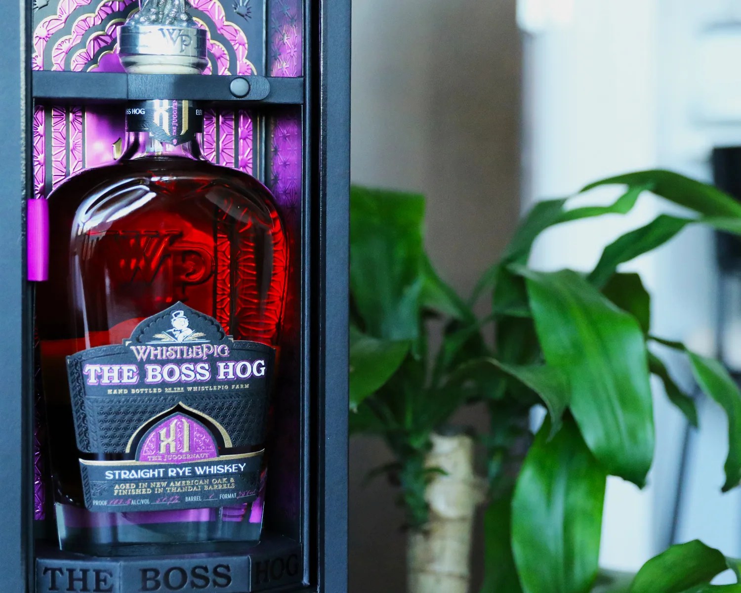 a bottle of whistlepig whiskey next to a house plant