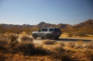 electric SUV parked on dirt street in desert surrounded by shrubs