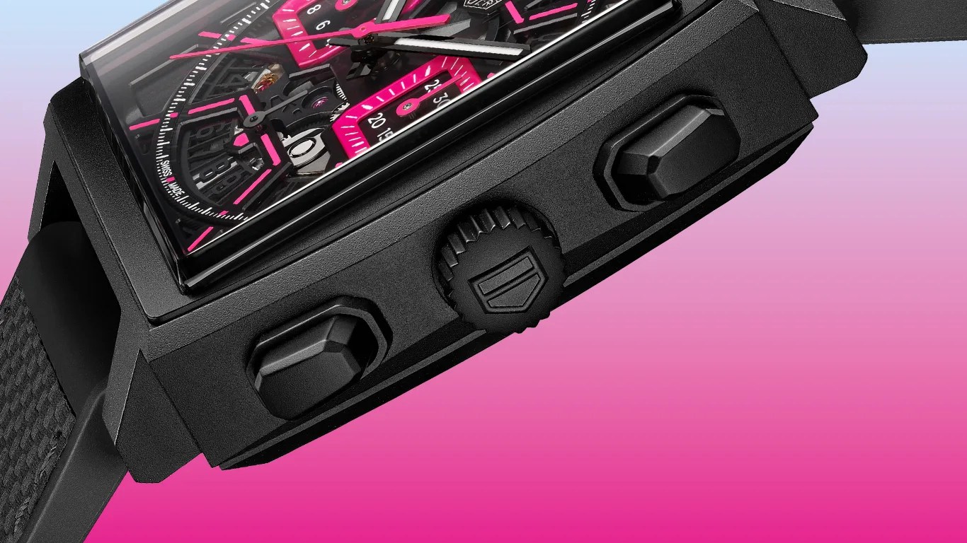 a closeup of a tag heuer monaco watch against a gradient pink background
