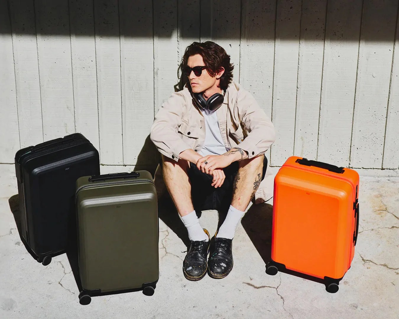 man sitting on floor next to three Aer Carry-On luggages