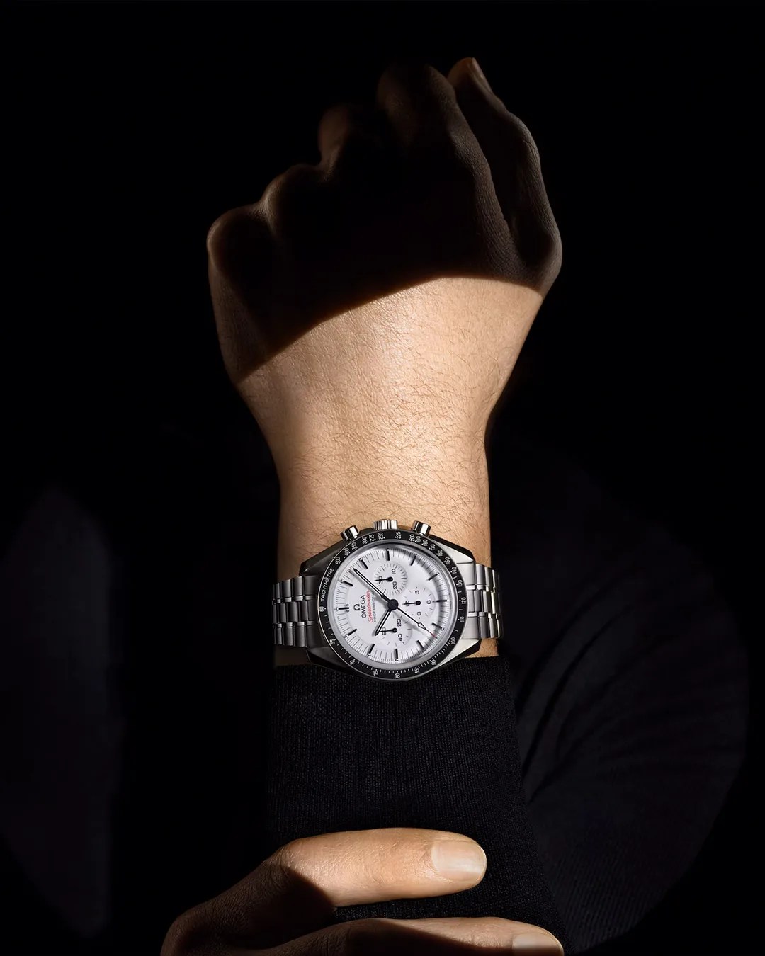 a fist pointing up to showcase a Omega Speedmaster Moonwatch Professional White Watch on their wrist