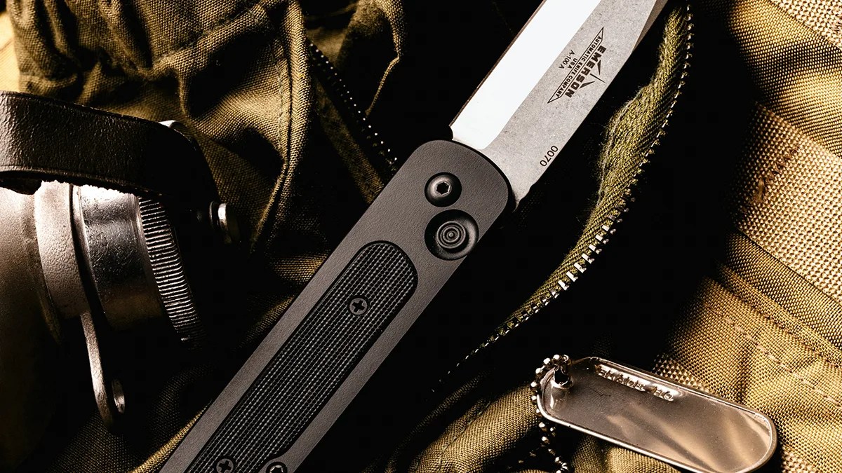 Closeup of Emerson A 100 Automatic Knife on tactical pack next to dog tags