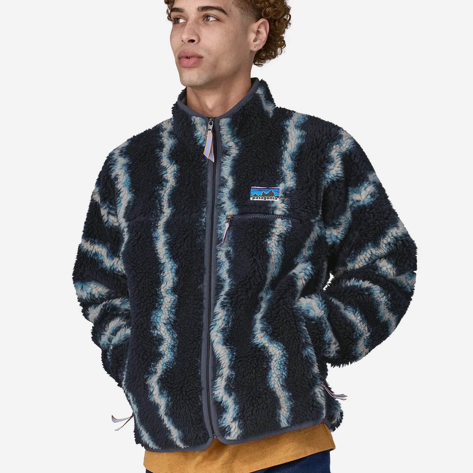 The Patagonia Natural Blend Retro Cardigan being worn by a male model looking to the left with his hands in the hand warmer pocket. 