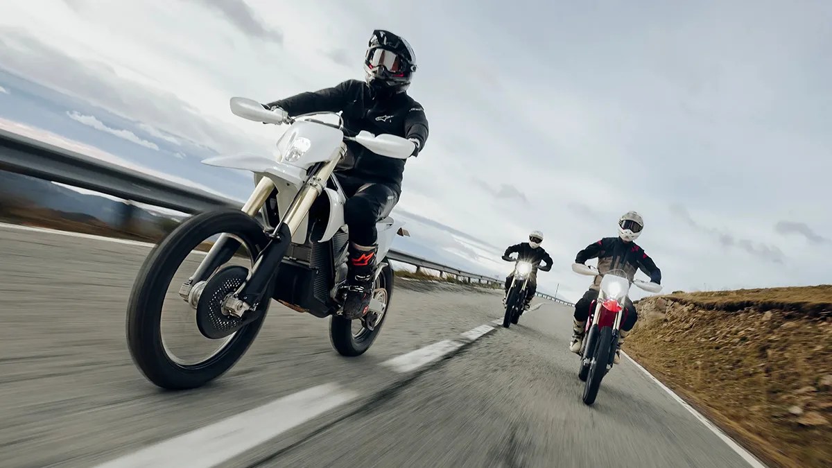 Three riders aboard Stark Varg EX motorcycles riding down mountain highway
