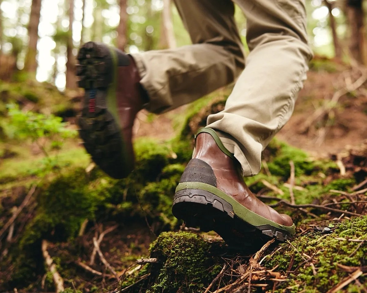 Person walking up mossy hillside wearing Xtratuf Legacy Altitude Low boots