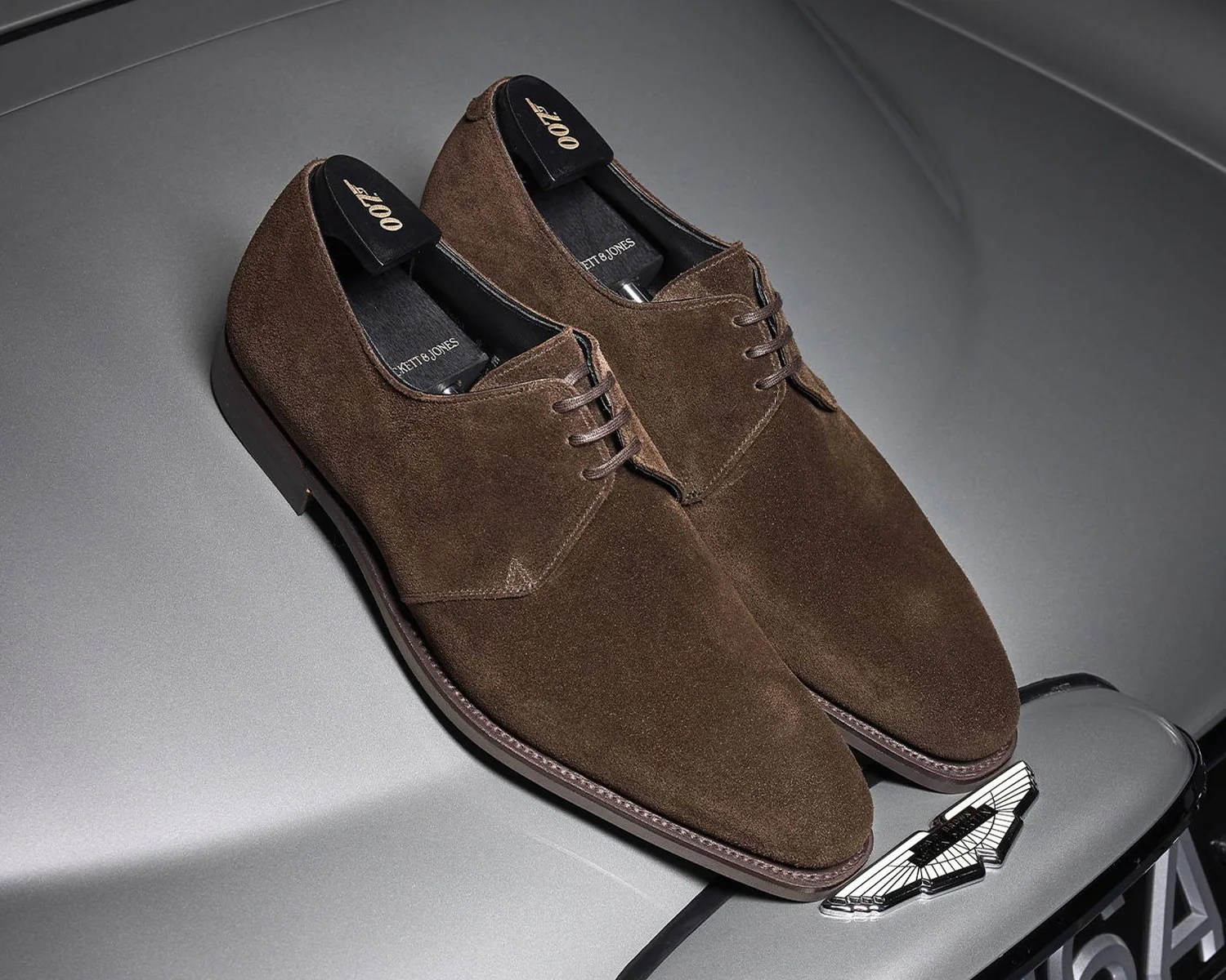 crockett and jones james bond shoes on the hood of an aston martin sports car