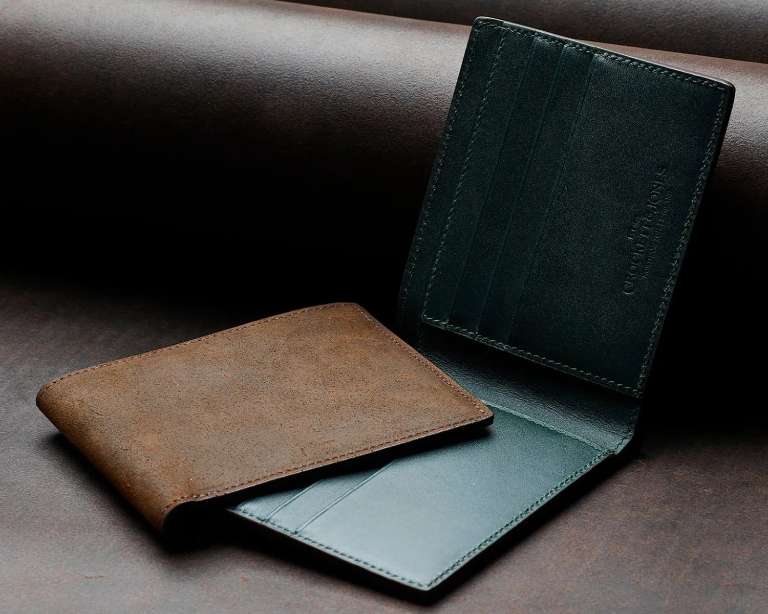 two crockett and jones suede wallets on a leather surface