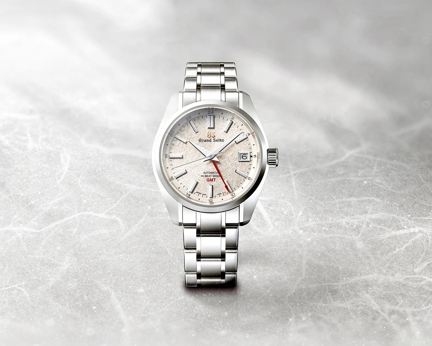 a grand seiko watch on a gray textured surface