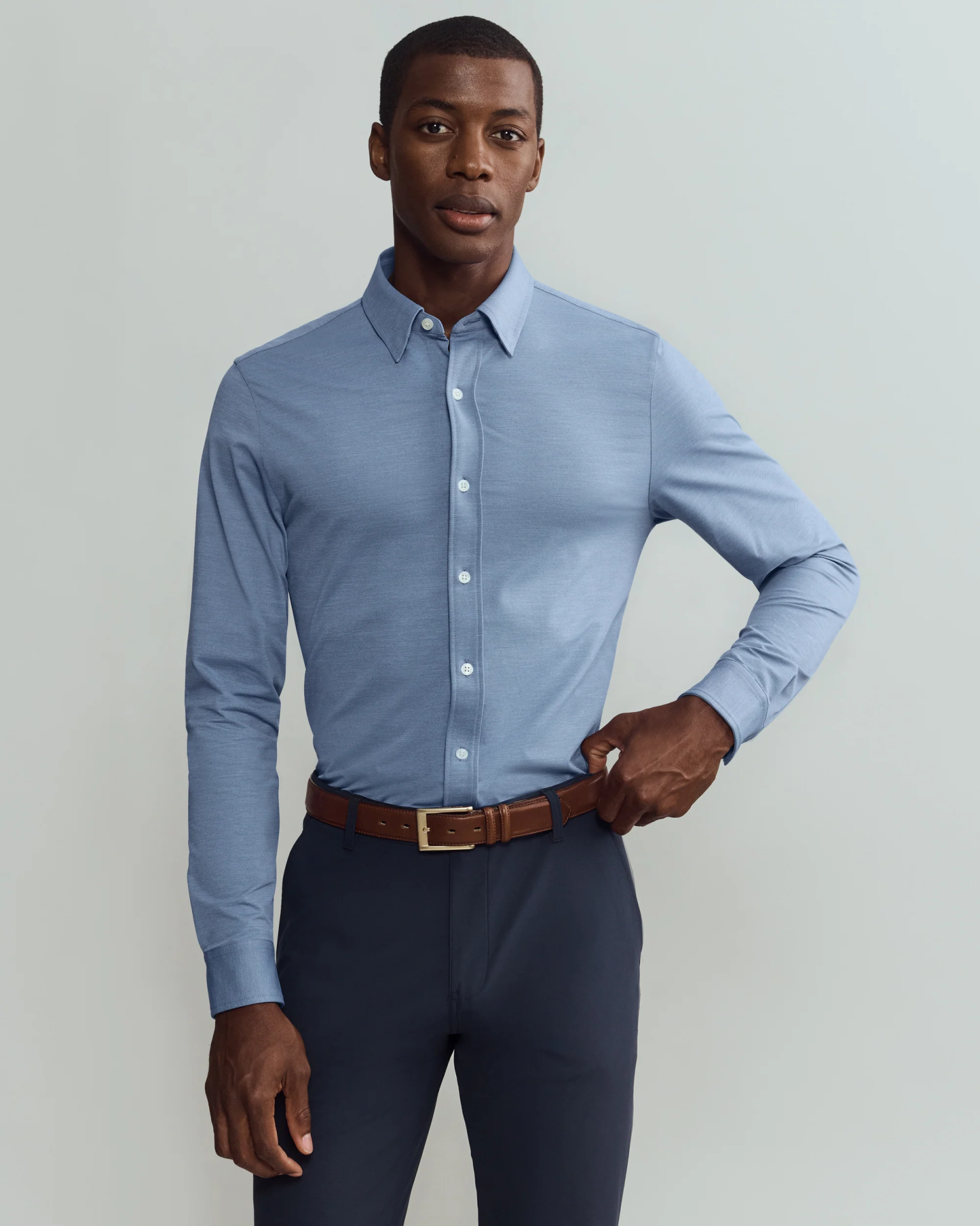 Rhone Commuter dress being worn on black male model. The model is facing forward and has one arm up on his waist.