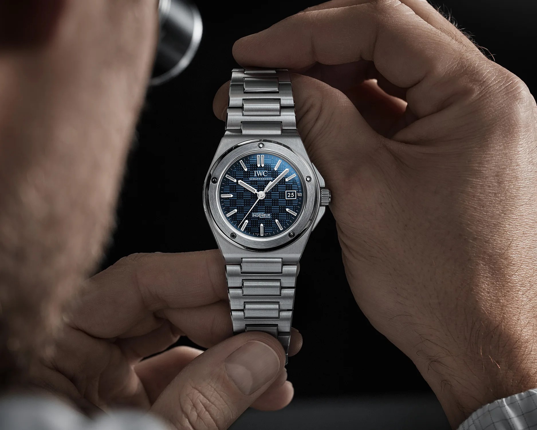 a man holds a blue iwc sports watch