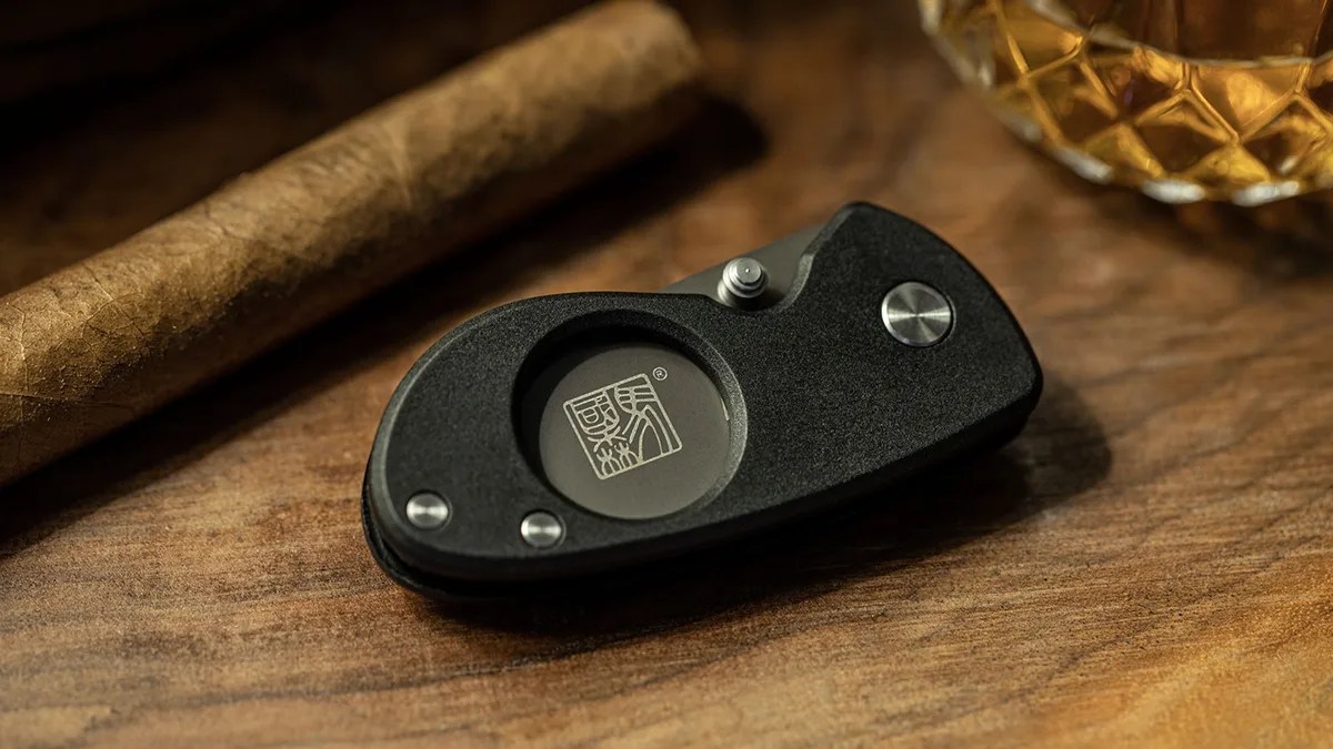 Al Mar Havana Clipper Cigar Cutter in front of cigar and whiskey glass on wood desk