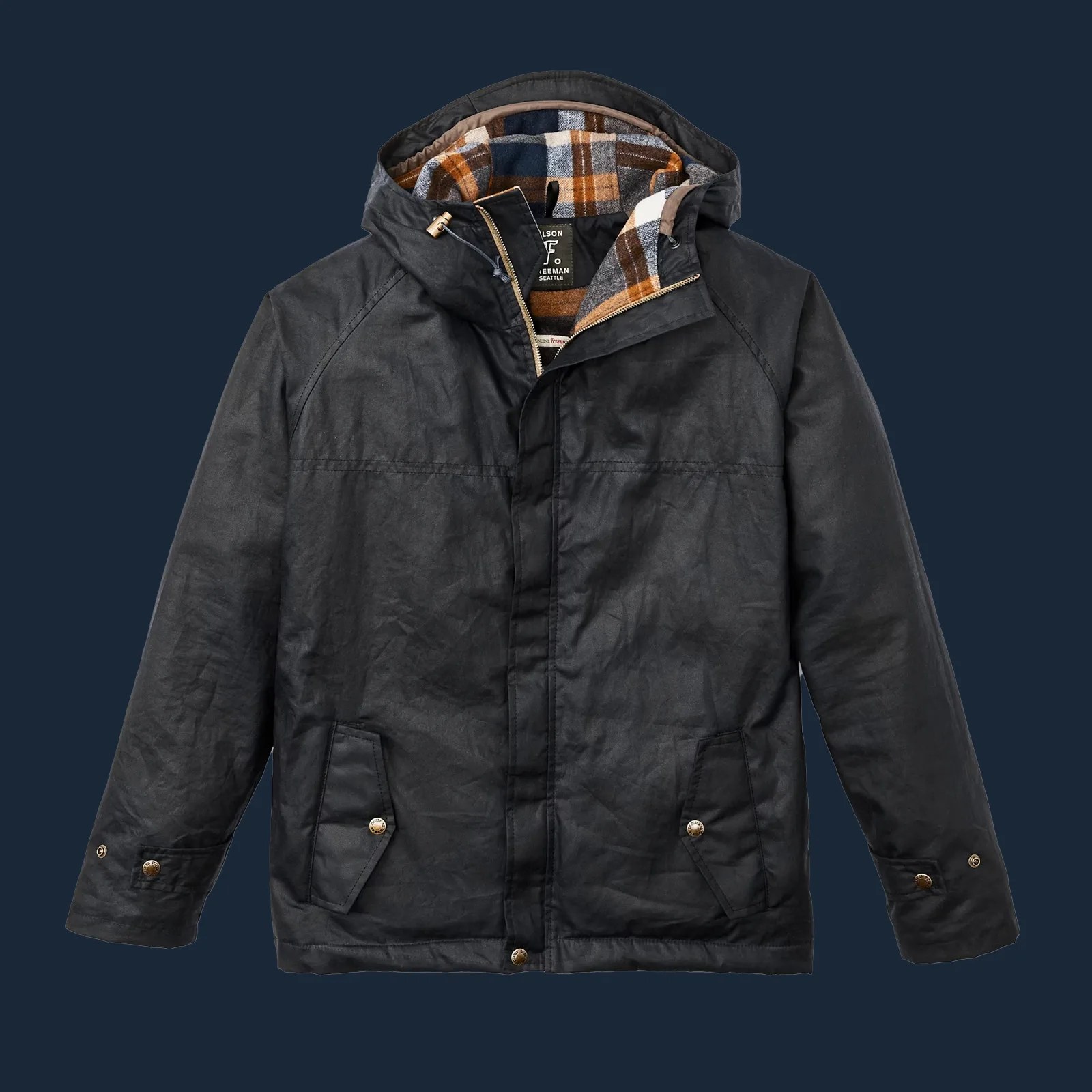 Filson x Freeman 2024 rainjacket shown zipped up and flat against a dark navy background. 