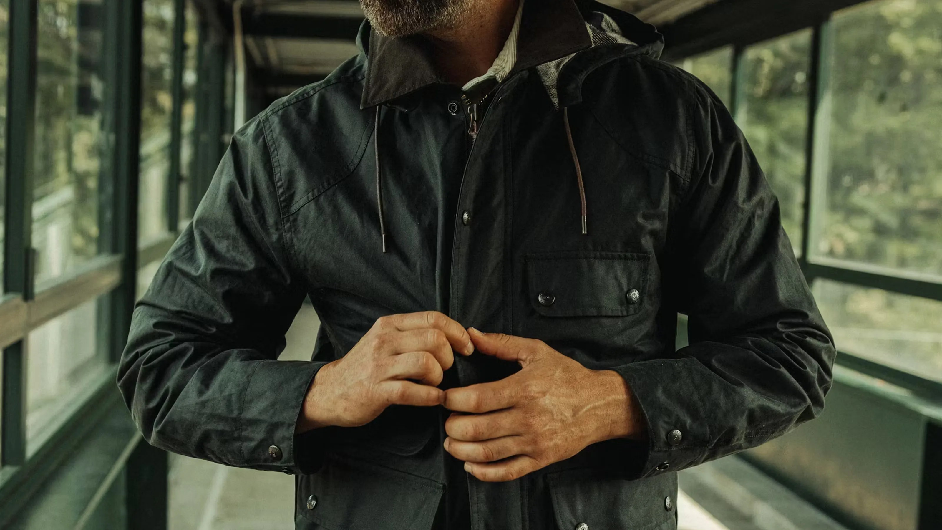 A close-up of the chest area of a man wearing Flint and Tinder's Flannel-lined waxed Hudson jacket in forest green
