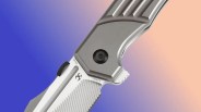 Closeup of Kansept Orion knife on blue-pink background