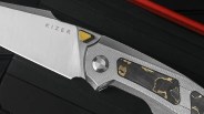 Closeup of Kizer Feweed knife on black background