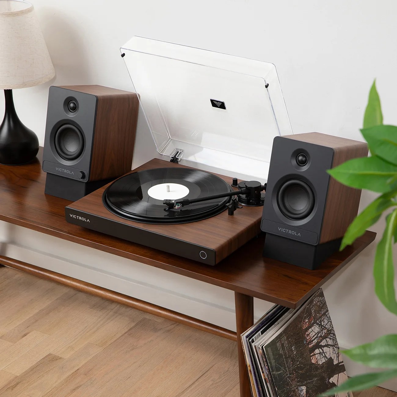 Wood-finished Victrola turntable with black vinyl record and matching speakers on a wooden table.