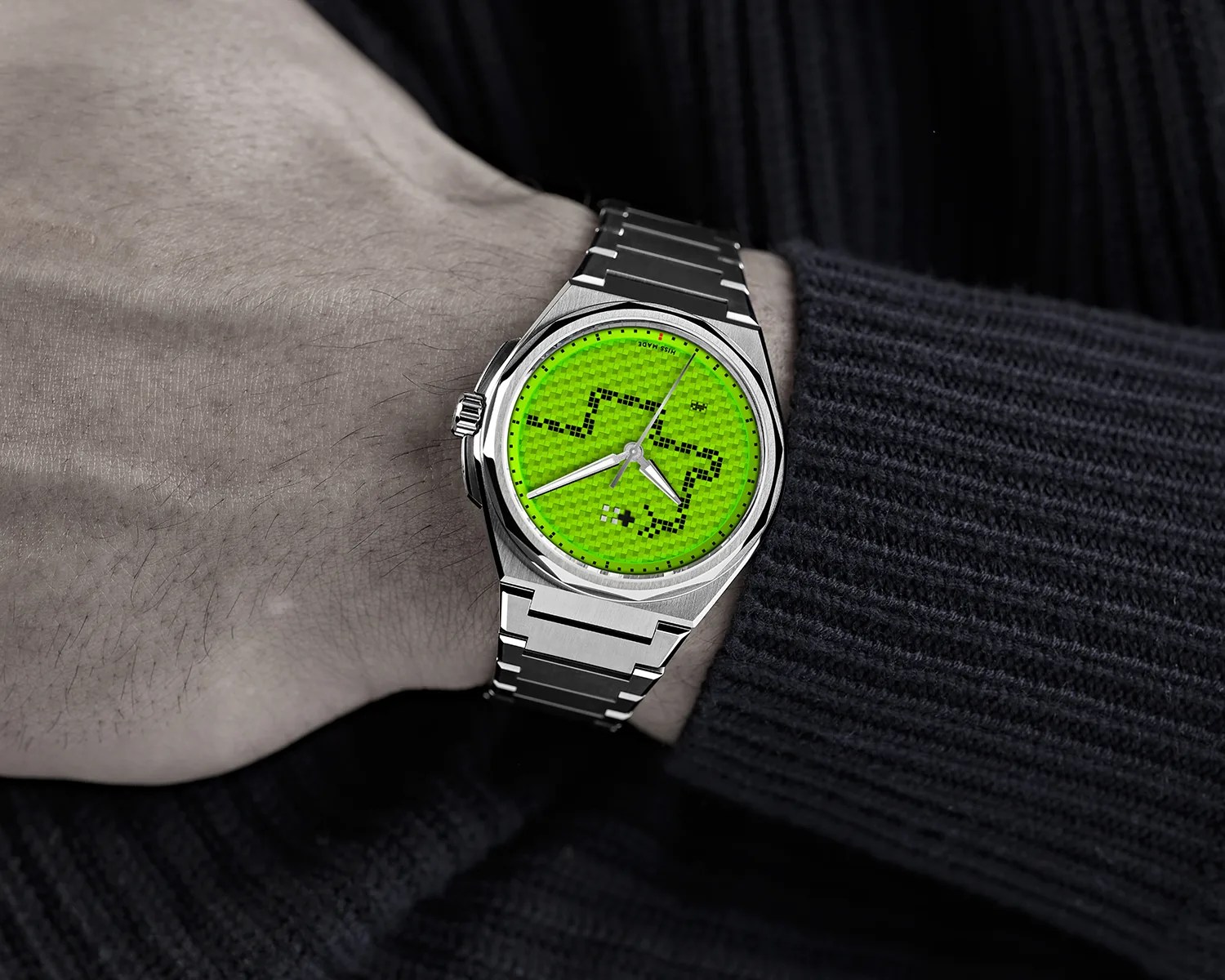a green christopher ward watch on the wrist of a man wearing a sweater