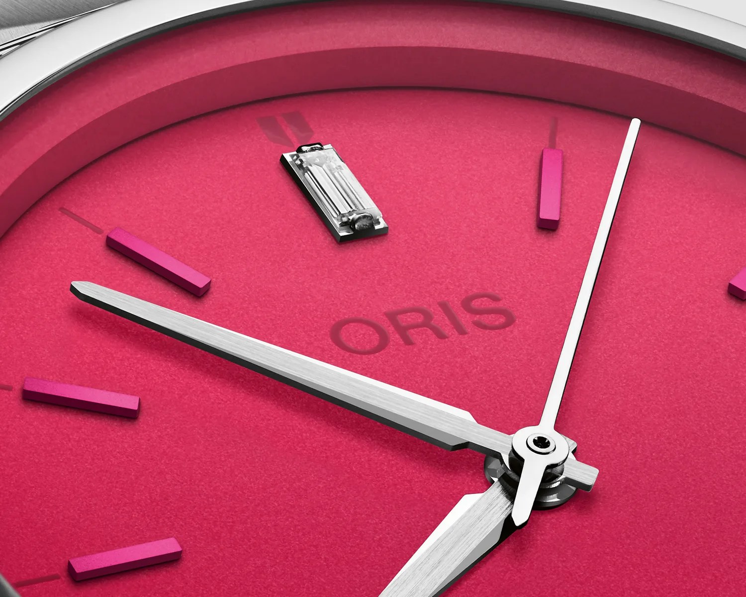 a closeup of a pink oris watch dial with a diamond