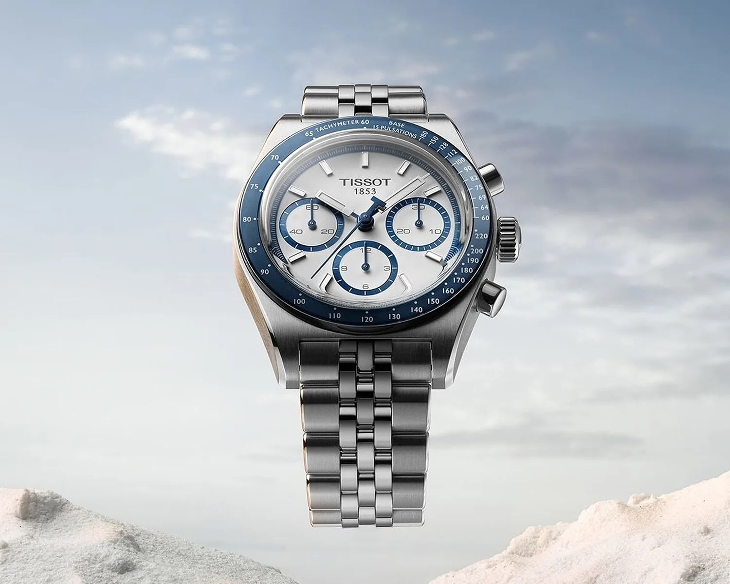 a tissot automatic chronograph over a sky and mountains