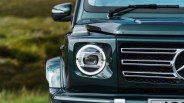A close up of the grill of the Mercedes-Benz G-Wagen in forest green showing the left headlight.