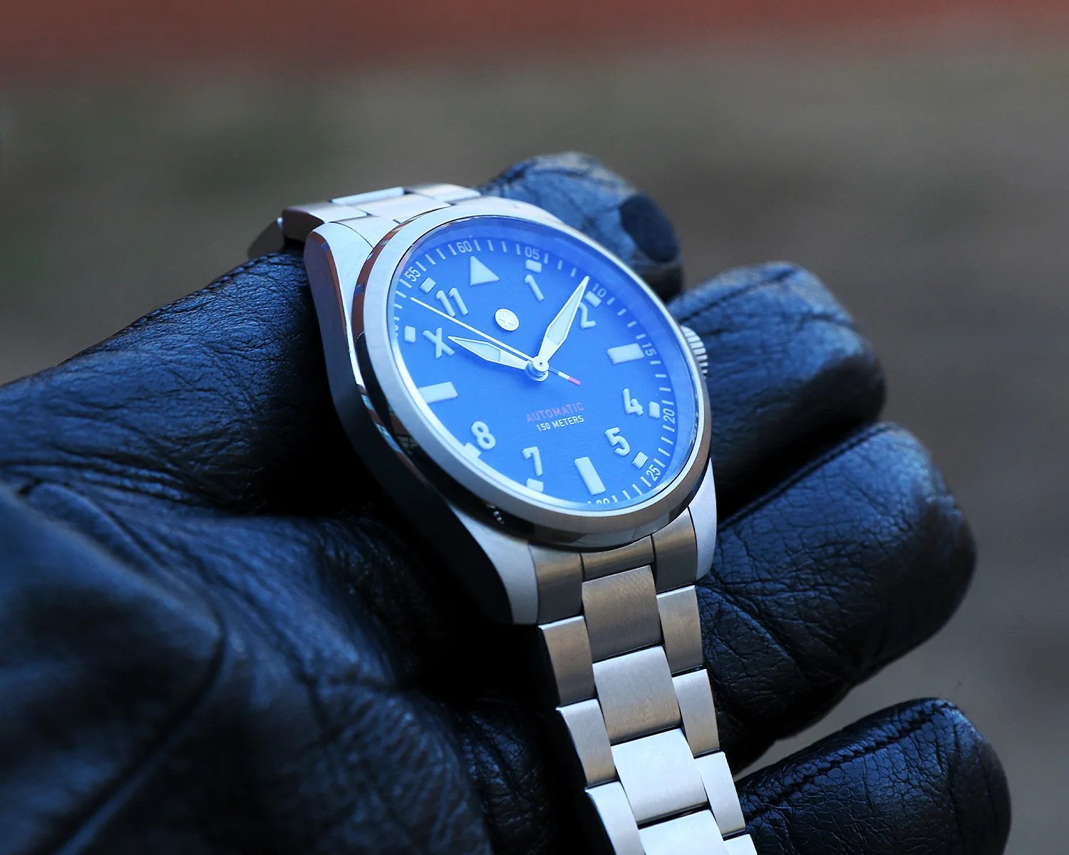 a jack mason pilots watch held by a leather gloved hand